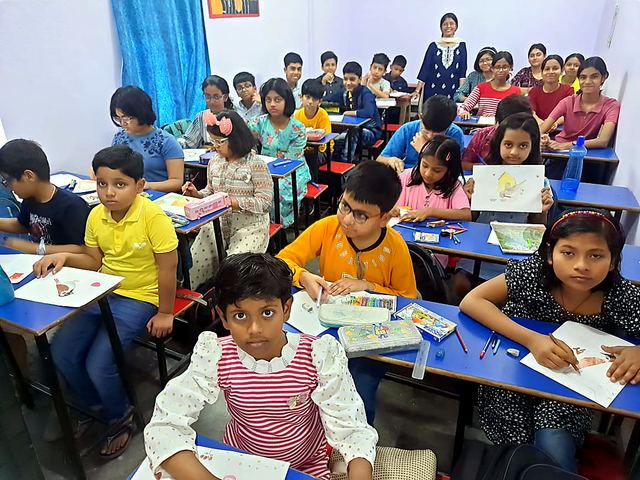 Large class of children drawing at desks in a hall