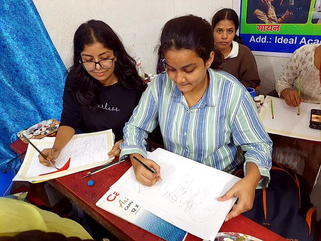 Two girl students drawing on sheets in an art class